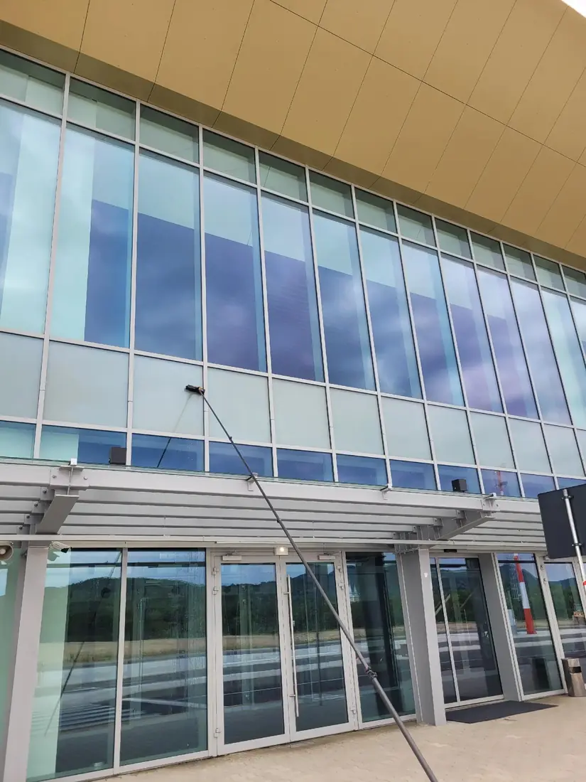 Tija telescopică întinsă pe fațada de sticlă a aeroportului