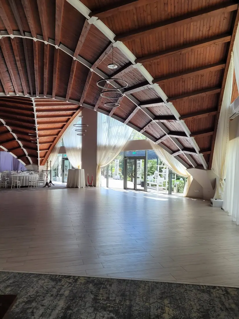 Sala de evenimente cu tavan din lemn în arc și vitraj pe toată lungimea